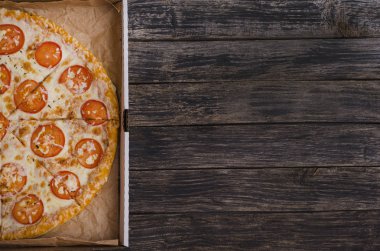 Peynirli ve domatesli pizza. Siyah ahşap arka planda fotokopi alanı olan bir kutuda. Menüler ve reklam pizzacıları için.