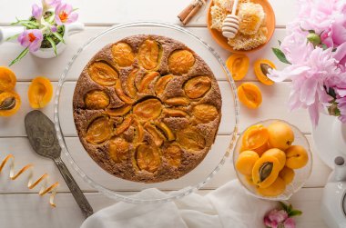Beyaz ahşap arka planda kayısı turtası ve şakayık buketi. Yukarıdan görüntüle.