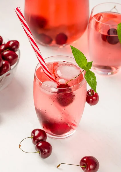 Summer cooling drink from sweet cherry with ice and mint on a white wooden background. Vertical photo