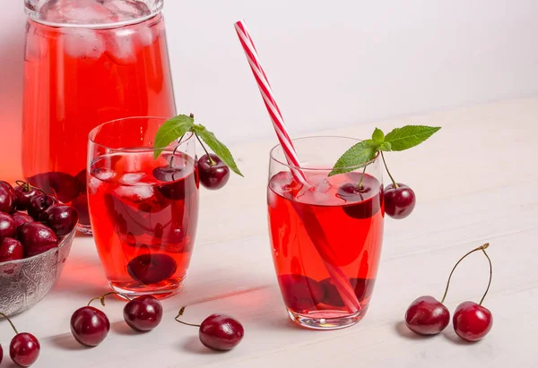 Summer cooling drink with cherries, ice and mint on a white background with copy space. Vertical photo