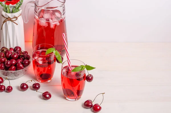 Summer cooling drink with cherries, ice and mint on a white background with copy space. Vertical photo