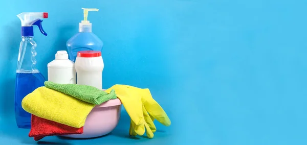 Background banner with home cleaning products with colorful napkins on a blue background with copy space. Cleaning in the house, in the apartment.