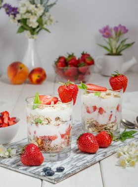 Beyaz ahşap arka planda yoğurtlu müsli ve taze çilek..