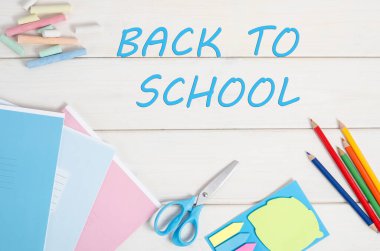 Okula geri döndüm. Okul malzemeleriyle beyaz ahşap arka plan üzerine yazı yazdım.