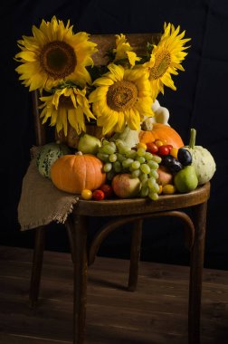 Sonbahar Cornucopia 'sı. Sebzelerden ayçiçekleri ve siyah arka planda meyvelerle dolu bir hayat. Şükran Günü ve hasat.