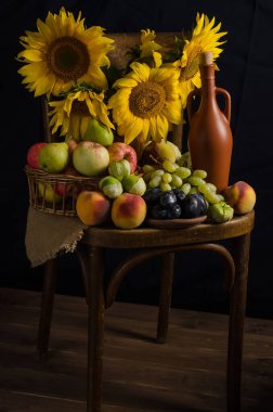 Sonbahar Cornucopia 'sı. Karanlık bir arka planda meyveler, üzümler ve şaraptan oluşan ayçiçekleri olan bir hayat. Şükran Günü ve hasat.