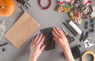 Cadılar Bayramı için bir hediyeyi adım adım paketliyorum. Dördüncü adım: Siyah kağıdı al ve ikiye katla.