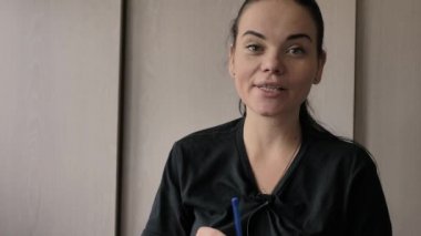 Güzel bir genç beyaz kız neşeli ilginç bir hikaye anlatıyor, aydınlık oda, ofis röportajlar verir. Uzun siyah saçlı, gri-yeşil gözleri, parmağında düğün yüzüğü, elinde mavi kalem var.