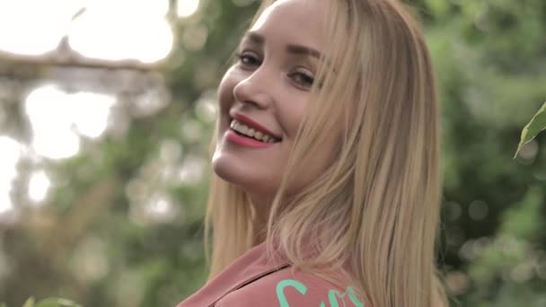 Beautiful girl with red lips and blue eyes smiles sweetly to someone aside — Stock Video