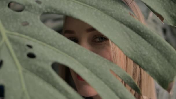 Beautiful green-eyed blonde looking at the camera in a tropical forest — Stock Video
