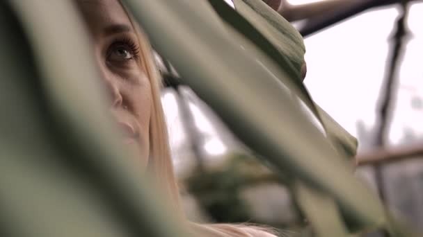 Hermosa rubia de ojos verdes mirando a la cámara en un bosque tropical — Vídeos de Stock