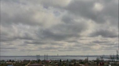 Nehrin karşısında yer alan sanayi bölgesinin panoraması. Gök gürültülü bulutlarda gökyüzü. Ön planda özel evler vardır. Sağ tarafta hidroelektrik var. Timelapse