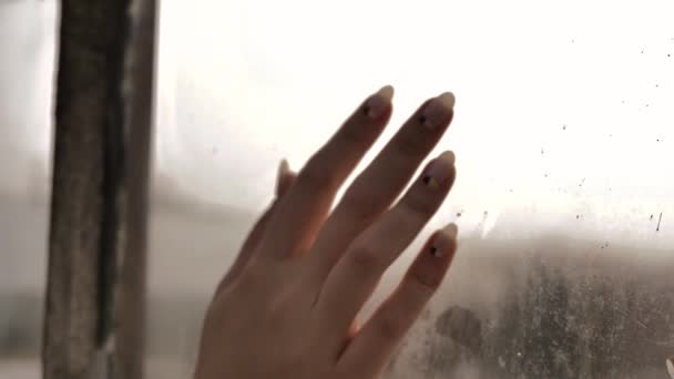 女性の手は霧の窓の上を滑り ガラスの上に筋を残す — ストック動画