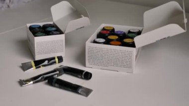 kumaş boya ve siyah tüpler çok renkli kavanoz ile iki paket beyaz bir yüzey üzerinde yalan