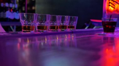 karanlık bir odada bir bar sayacı üzerinde alkol ve bir kokteyl ve bir saman ile beş bardak vardır. Barmen kız bir içki için uzandı