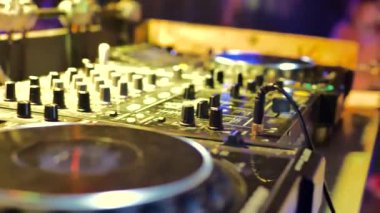 erkek el Dj konsolu kontrol eder. Oda sarı ışıkla aydınlatılmış..