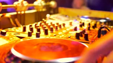 erkek el Dj konsolu kontrol eder. Oda sarı ışıkla aydınlatılmış..