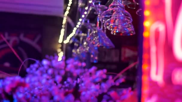 Barın Üstünde Kırmızı Mavi Işıklarla Aydınlatılmış Şarap Bardakları Asılı Çiçeklere — Stok video