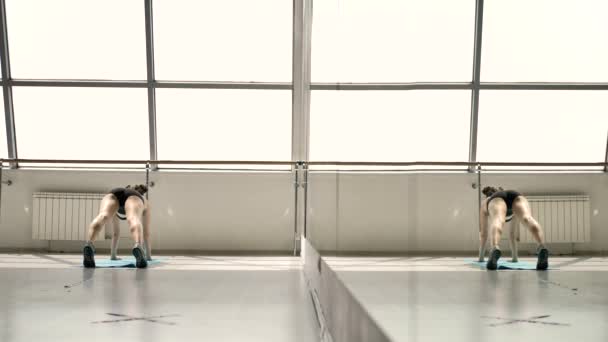 床にストレッチエクササイズを行う黒のスポーツウェアの白人ブルネット 背景には ステンドグラスの窓 バレリーナのための機械で彼女の反射 — ストック動画