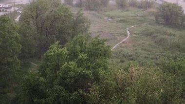 Kar yağışı ve yaz aylarında şiddetli yağmur. Arka planda yeşil ağaçlar, çimenler, patika lar var. Yukarıdan görüntüleyin. Anormal doğal fenomen. Yavaş çekim.