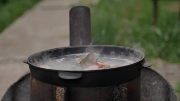 Vaření rybí polévky venku, na hladině vodní pěny a hojné páry, na konci záběru, léto