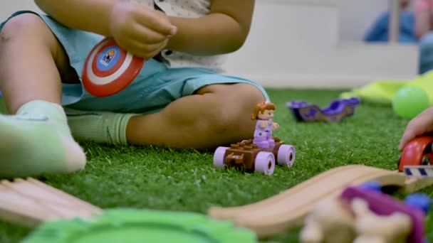 Mãos Uma Criança Pequena Jogar Brinquedo Plástico Sentado Grama Artificial — Vídeo de Stock