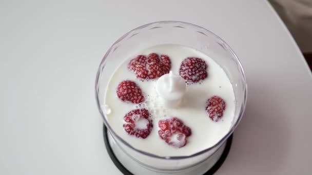 特写镜头 女性双手将草莓放入牛奶中 放在一个透明的搅拌杯中 搅拌机站在白色桌子上 顶视图 — 图库视频影像