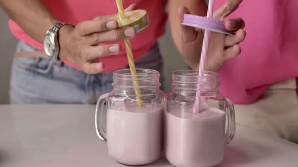 Female Hands Pour Pink Milkshake Transparent Glass Goblet Next Girl — Stock Video