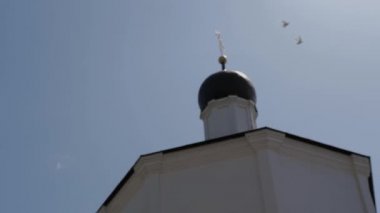 Ortodoks Kilisesi 'nin kubbesine yakın iki beyaz güvercin uçuyor. Bokeh 'te patlıyorlar. Güneşli yaz günü.