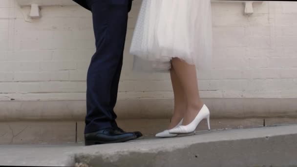 Menyasszony Vőlegény Lábai Egymással Szemben Állnak Háttérben Egy Fehér Téglaépület — Stock videók