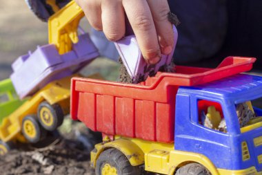 çocuk kum ile sokakta oynuyor; o damperli kamyon oyuncak içine toprak ile ekskavatör kova yükler