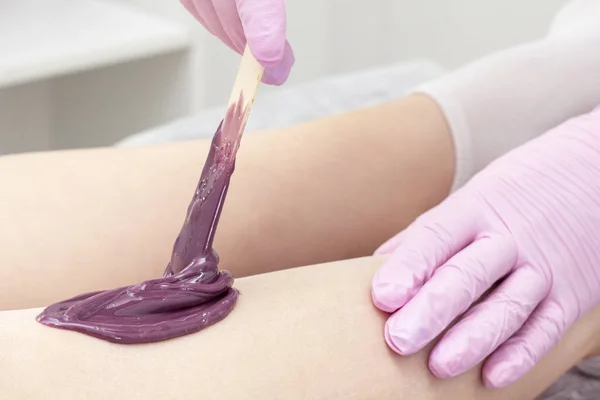 waxing cosmetic depilation procedure warm wax applied to the skin with a wooden stick