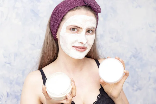girl with a face mask holding a jar with a face mask and a lid from a jar with a copy space