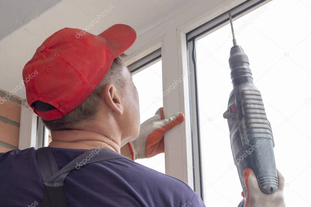 Worker installs windows craftsmen screw the frame to the wall Repair in a high-rise building