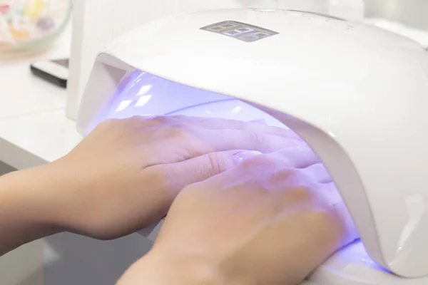 UV lamp for drying varnish for two hands. girl dries shellac on two hands in a lamp