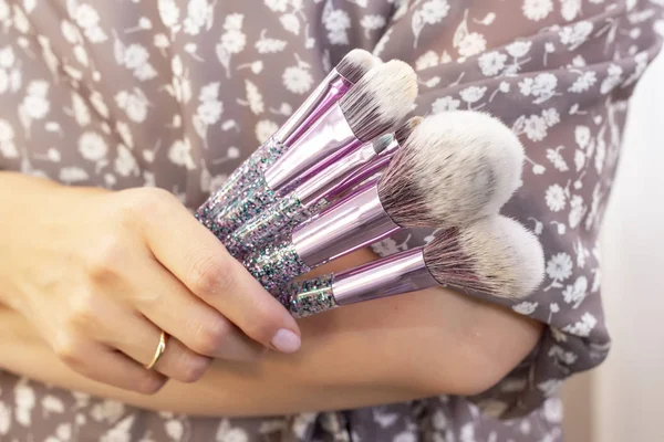 Makeup artist puts makeup on girl model. holding a set of makeup brushes