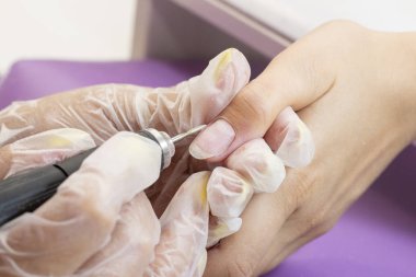 Tırnak levhasının öğütülmesi ve işlenmesi. Manikür ustası müşteriye manikür yapıyor. Jöle sürmeden önce oje sürüyorum. shellac