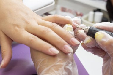 Tırnak levhasının öğütülmesi ve işlenmesi. Manikür ustası müşteriye manikür yapıyor. Jöle sürmeden önce oje sürüyorum. shellac