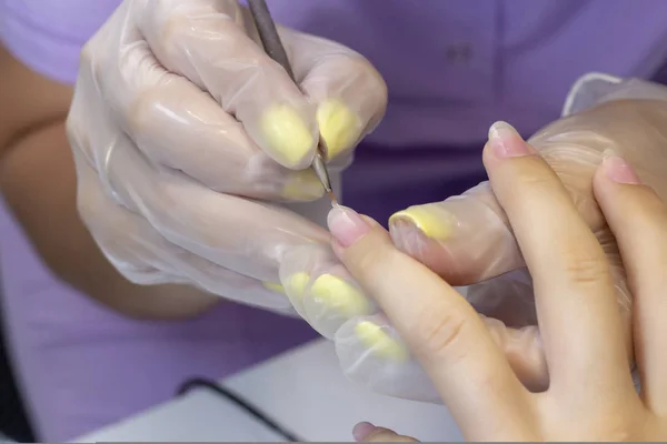 drawing a transparent basis for varnish gel. shellac. manicurist makes manicure in the salon