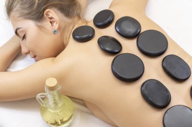 Spa sıcak taş masajı. Spa salonunda masaj yatağında yatan çekici güzel kız. Spa aroma terapi ve güzellik bakımları kavramı