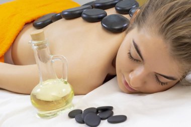 Spa sıcak taş masajı. Profesyonel güzellik uzmanı, taşlarla kadına masaj yapıyor. Sağlıklı yaşam merkezinde vücut tedavisi zevk rahat kız