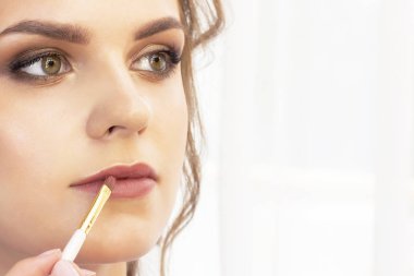 Makyaj sanatçısı modele makyaj uygular. ruj için dudak boyası fırçası. güzel kız modeli, portre. Makyajçıplak renkler. düğün, akşam makyajı. kopyalama alanı