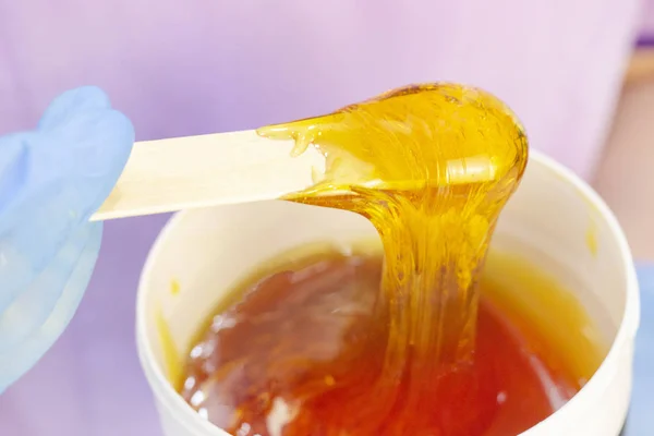 Liquid sugar for skin epilation. Close up shot. depilation and beauty concept - sugar paste or wax honey for hair removing with wooden waxing spatula sticks