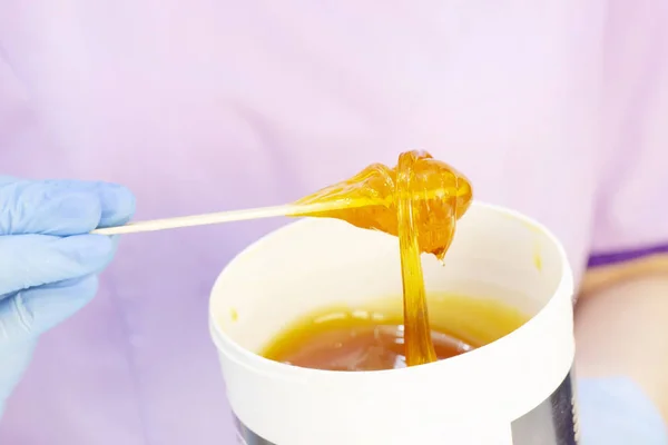 Liquid sugar for skin epilation. Close up shot. depilation and beauty concept - sugar paste or wax honey for hair removing with wooden waxing spatula sticks