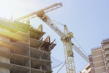 Şantiye arka planı. Vinçler ve yeni çok katlı binalar kaldırma. kule vinç ve bitmemiş yüksek katlı bina.