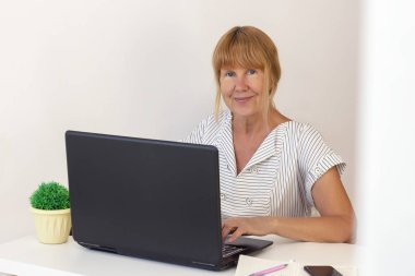 dizüstü bilgisayar kullanarak kıdemli kadın. ofiste bir dizüstü bilgisayar üzerinde çalışan iş kadını