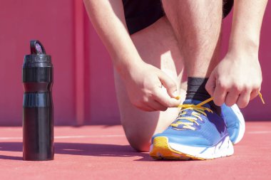 İçme suyu konsepti. erkekler koşucu su şişesi yanında ayakkabısını bağlama