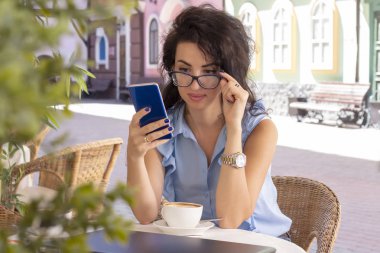 kafede dizüstü bilgisayar ve telefon ile uzaktan çalışan cam kadın. Kafede dizüstü bilgisayar kullanan güzel esmer. Mutlu iş kadını cep telefonu arama ve alma. Serbest