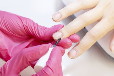 Tırnak eti için besleyici yağ uygulaması. Manikürcü bir kıza manikür yapıyor. küpartikül besin