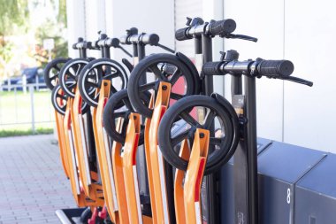 Otoparkta elektrikli scooter 'ı paylaşıyoruz. Scooter kiralama istasyonu. Yeni iş ortaklığı projesi. İnsanlar akıllı telefon kullanarak paylaşılan scooter 'ın QR kodunu tarıyor. Elictric Scooter çubuk ve kontrol paneli 